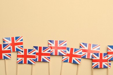 Small paper flags of United Kingdom on beige background, top view. Space for text