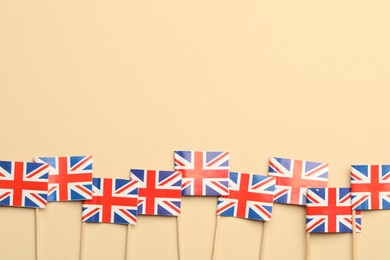 Photo of Small paper flags of United Kingdom on beige background, top view. Space for text