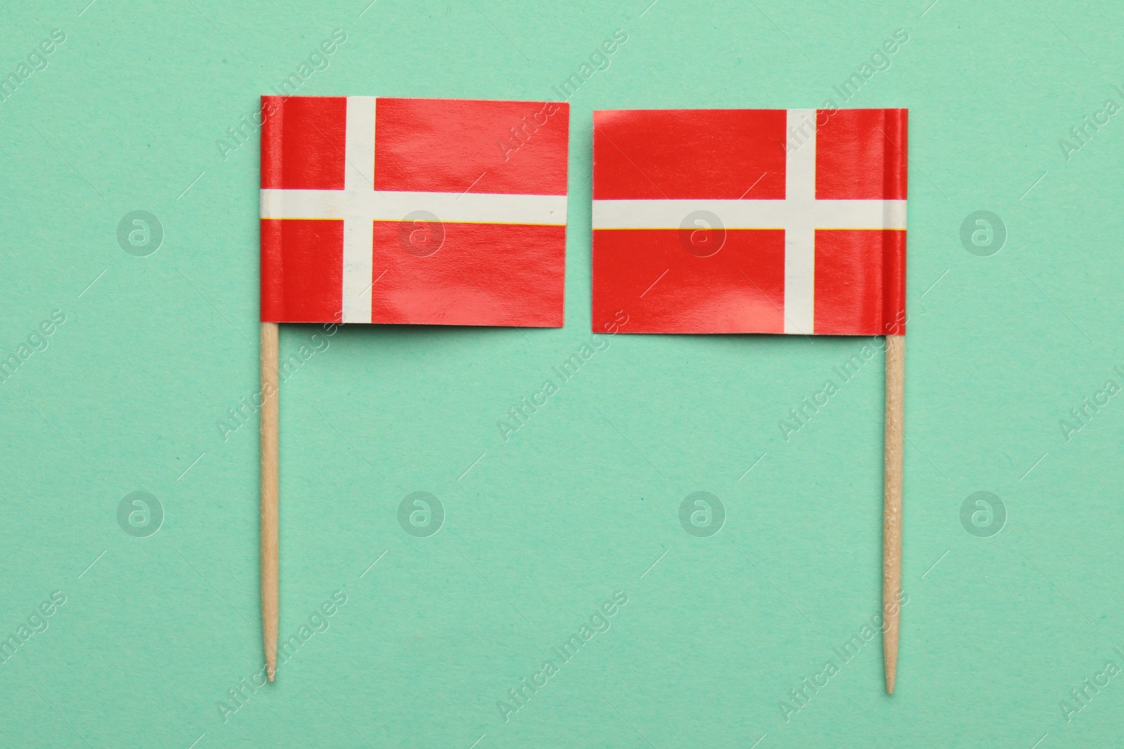 Photo of Small paper flags of Denmark on turquoise background, top view