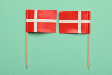 Small paper flags of Denmark on turquoise background, top view