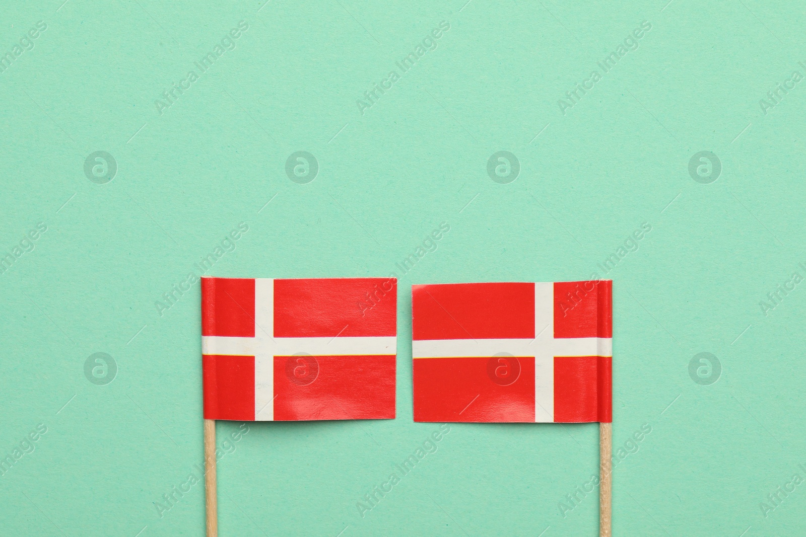 Photo of Small paper flags of Denmark on turquoise background, top view