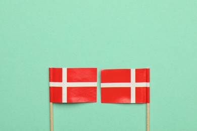 Photo of Small paper flags of Denmark on turquoise background, top view