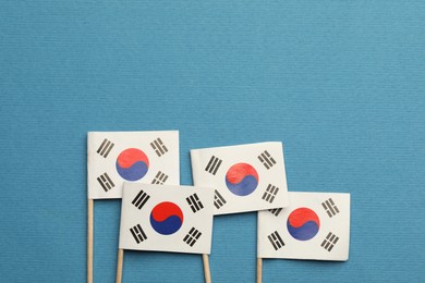 Photo of Small paper flags South Korea on light blue background, top view