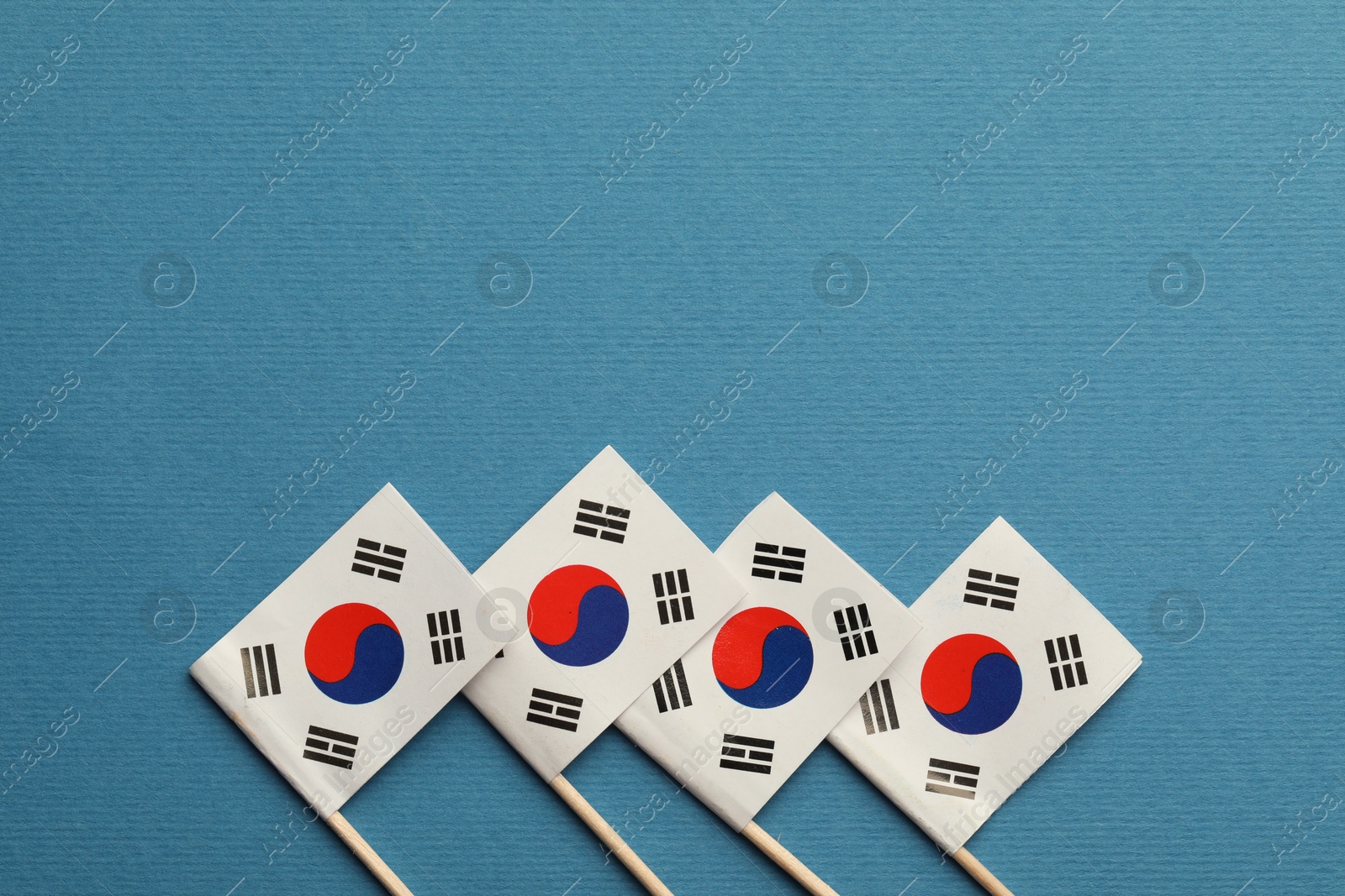 Photo of Small paper flags South Korea on light blue background, top view