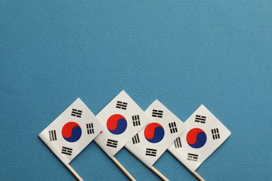 Small paper flags South Korea on light blue background, top view