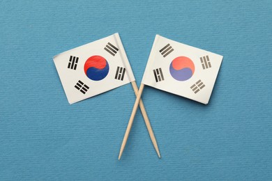 Small paper flags South Korea on light blue background, top view