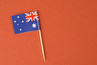 Small paper flag of Australia on orange background, top view. Space for text