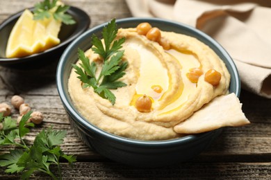 Delicious hummus with olive oil, chickpeas and pita on wooden table, closeup