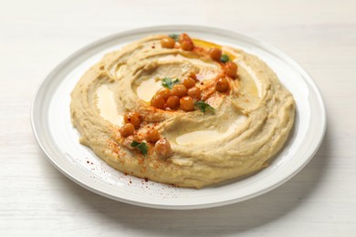 Photo of Delicious hummus with olive oil, chickpeas and paprika on white wooden table