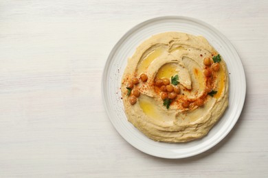 Photo of Delicious hummus with olive oil, chickpeas and paprika on white wooden table, top view. Space for text