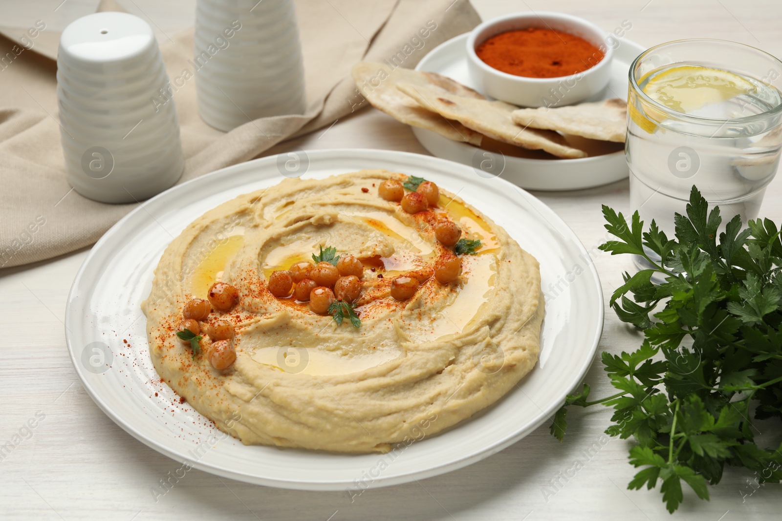 Photo of Delicious hummus with olive oil, chickpeas and paprika served on white wooden table