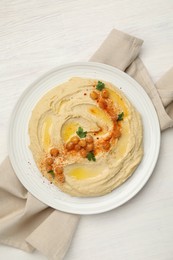 Photo of Delicious hummus with olive oil, chickpeas and paprika on white wooden table, top view