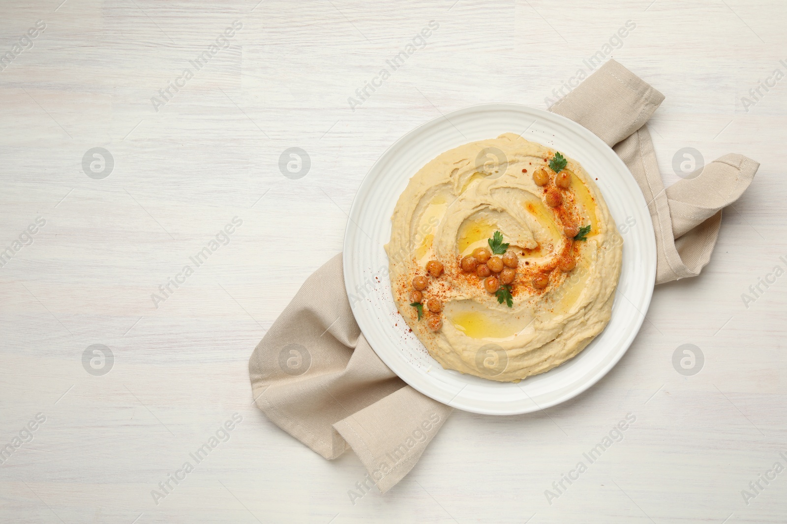 Photo of Delicious hummus with olive oil, chickpeas and paprika on white wooden table, top view. Space for text