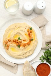 Photo of Delicious hummus with olive oil, chickpeas and paprika served on white wooden table, flat lay