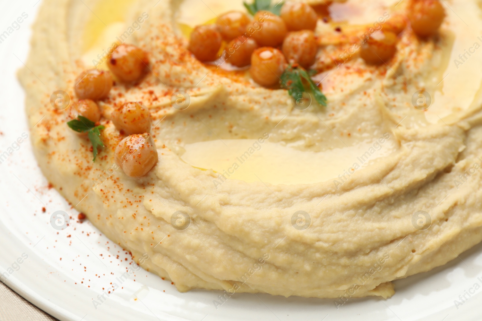 Photo of Delicious hummus with olive oil, chickpeas and paprika on table, closeup