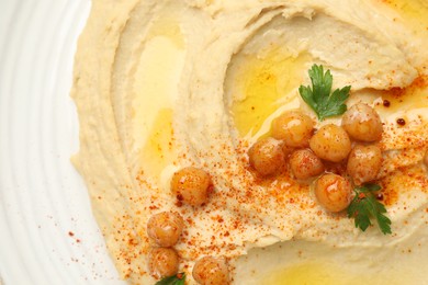 Photo of Delicious hummus with olive oil, chickpeas and paprika on plate, top view