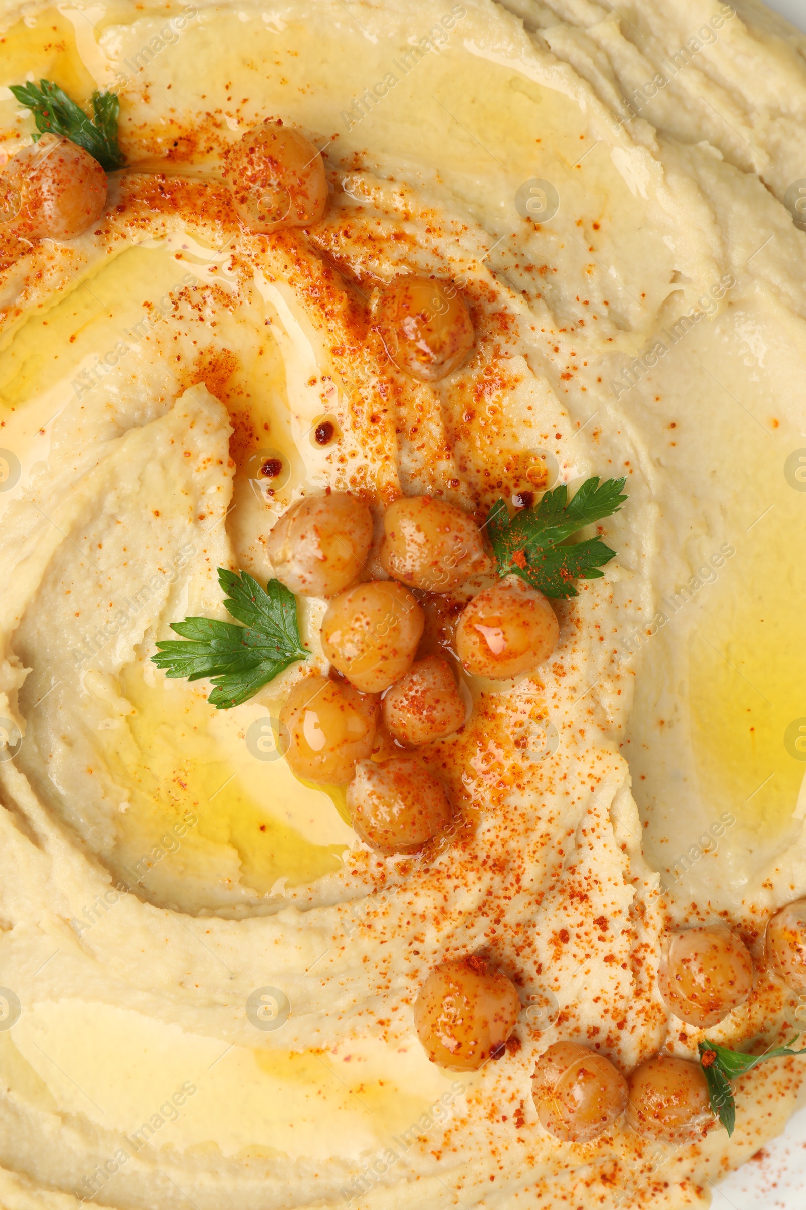 Photo of Delicious hummus with olive oil, chickpeas and paprika on plate, top view