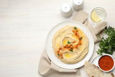 Photo of Delicious hummus with olive oil, chickpeas and paprika served on white wooden table, flat lay. Space for text