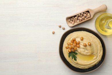 Photo of Delicious hummus with olive oil, chickpeas and parsley on white wooden table, flat lay. Space for text