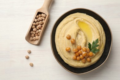 Delicious hummus with olive oil, chickpeas and parsley on white wooden table, flat lay