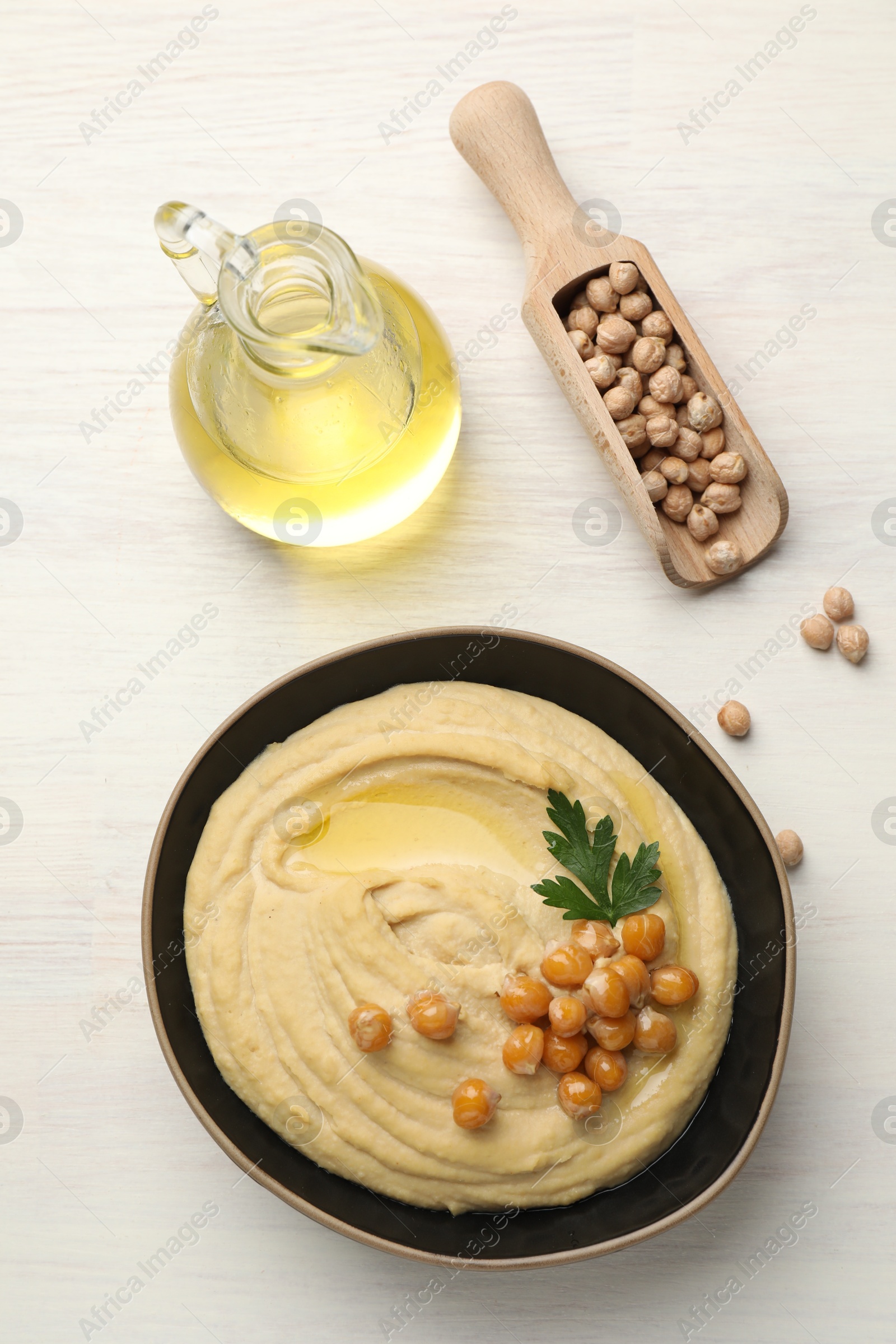 Photo of Delicious hummus with olive oil, chickpeas and parsley on white wooden table, flat lay