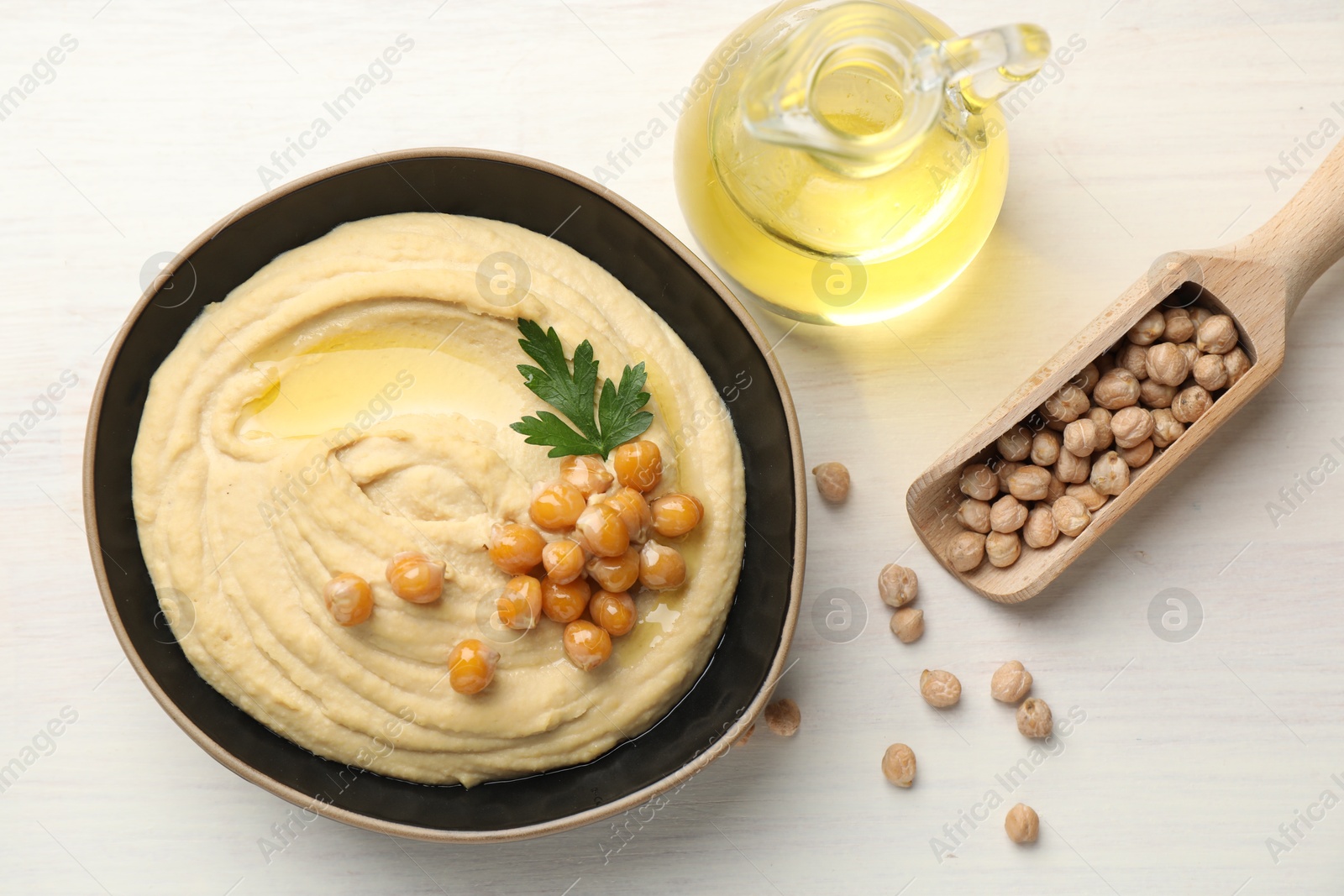 Photo of Delicious hummus with olive oil, chickpeas and parsley on white wooden table, flat lay