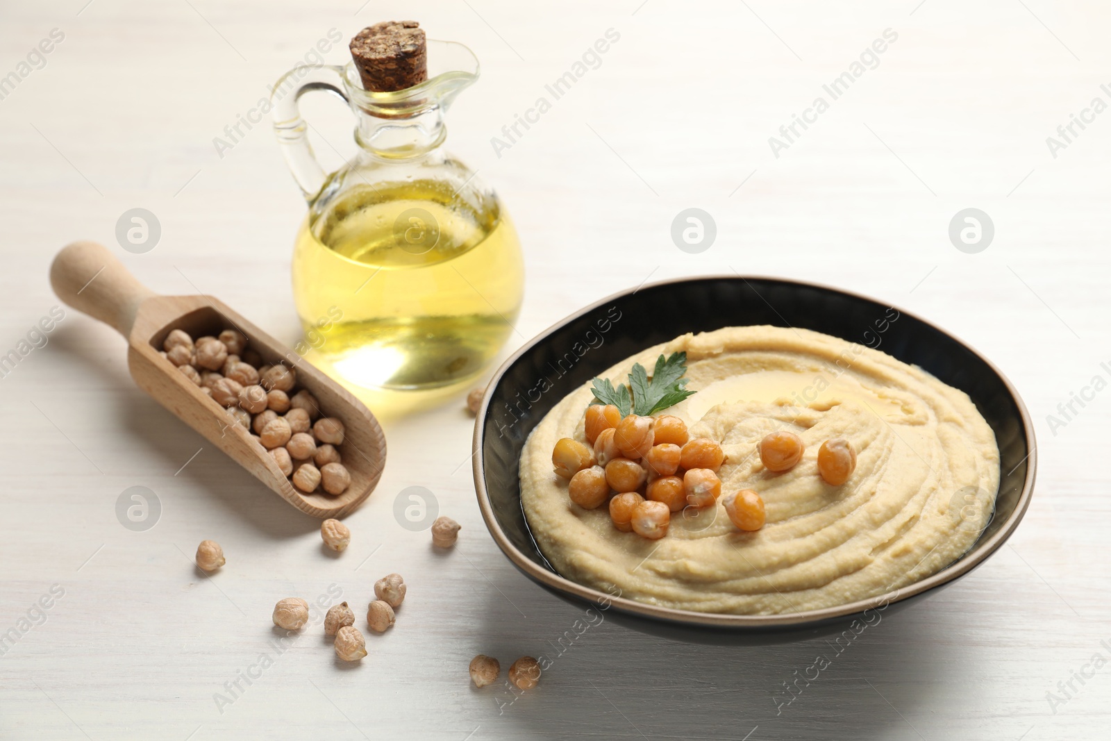 Photo of Delicious hummus with olive oil, chickpeas and parsley on white wooden table