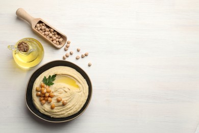 Delicious hummus with olive oil, chickpeas and parsley on white wooden table, flat lay. Space for text