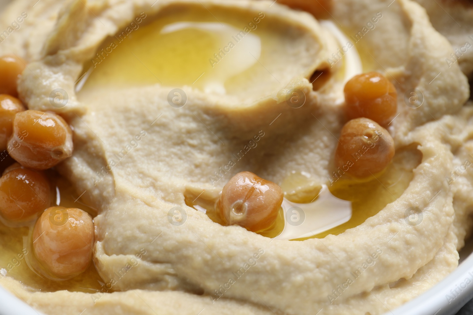 Photo of Delicious hummus with olive oil and chickpeas in bowl, closeup