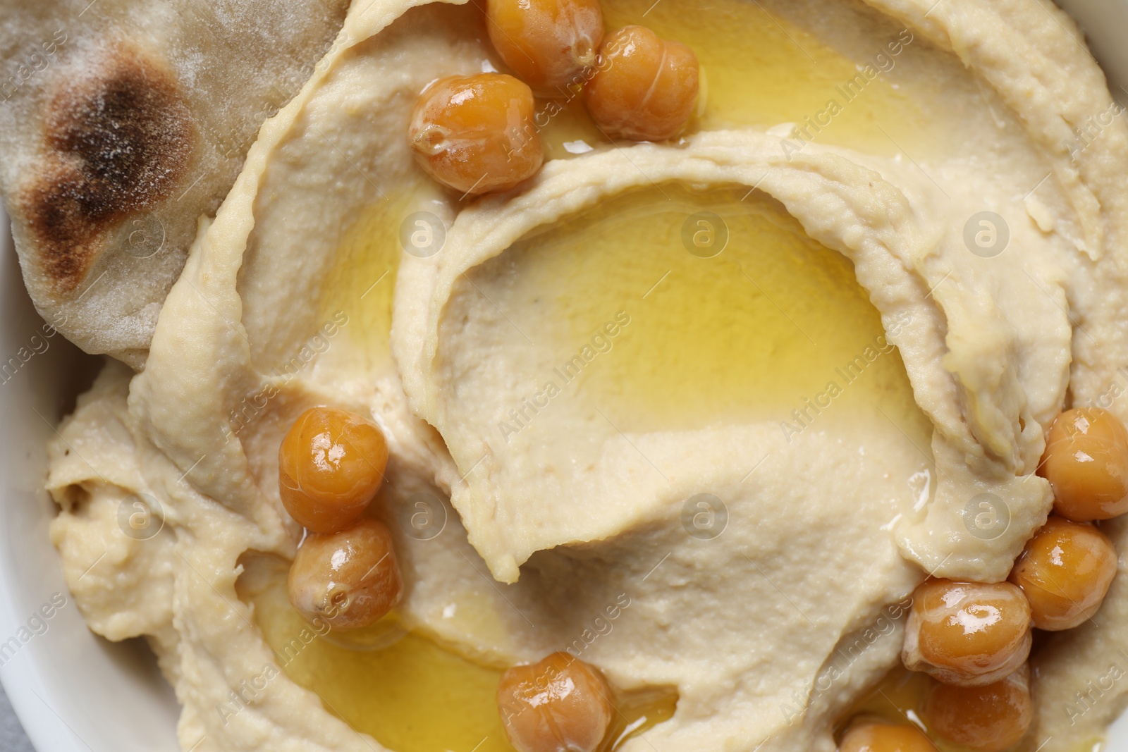 Photo of Delicious hummus with olive oil and chickpeas in bowl, top view