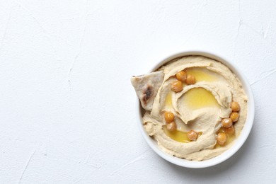 Photo of Delicious hummus with olive oil, chickpeas and pita in bowl on light textured table, top view. Space for text