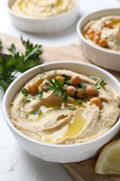 Delicious hummus with olive oil, chickpeas and parsley served on light table