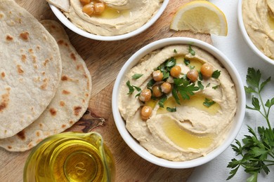 Photo of Delicious hummus with olive oil and chickpeas served on white table, flat lay