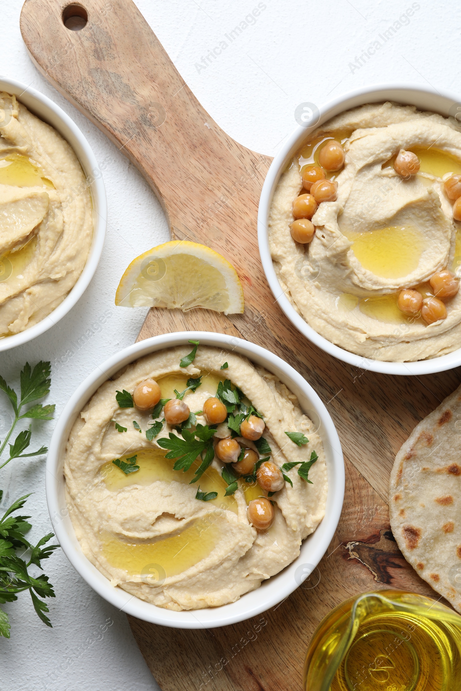 Photo of Delicious hummus with olive oil and chickpeas served on white table, flat lay