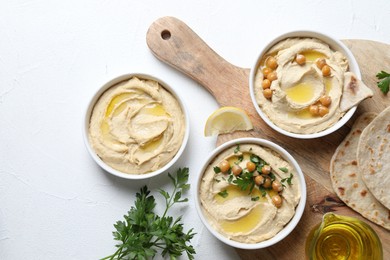 Photo of Delicious hummus with olive oil and chickpeas served on white table, flat lay