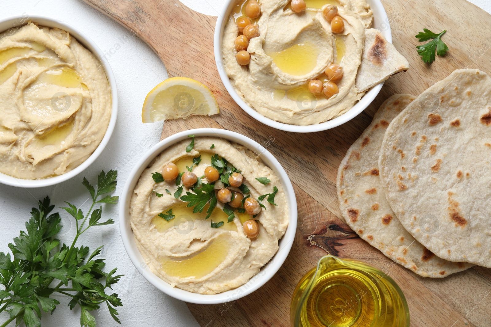 Photo of Delicious hummus with olive oil and chickpeas served on white table, flat lay