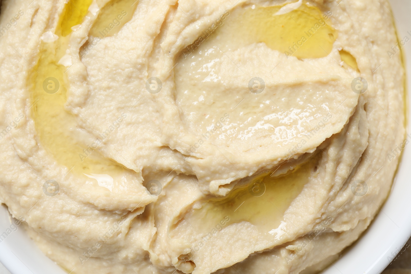 Photo of Delicious hummus with olive oil in bowl on table, top view