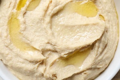 Photo of Delicious hummus with olive oil in bowl on table, top view