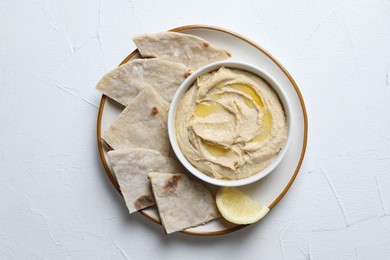 Photo of Delicious hummus with olive oil in bowl and pita on light textured table, top view