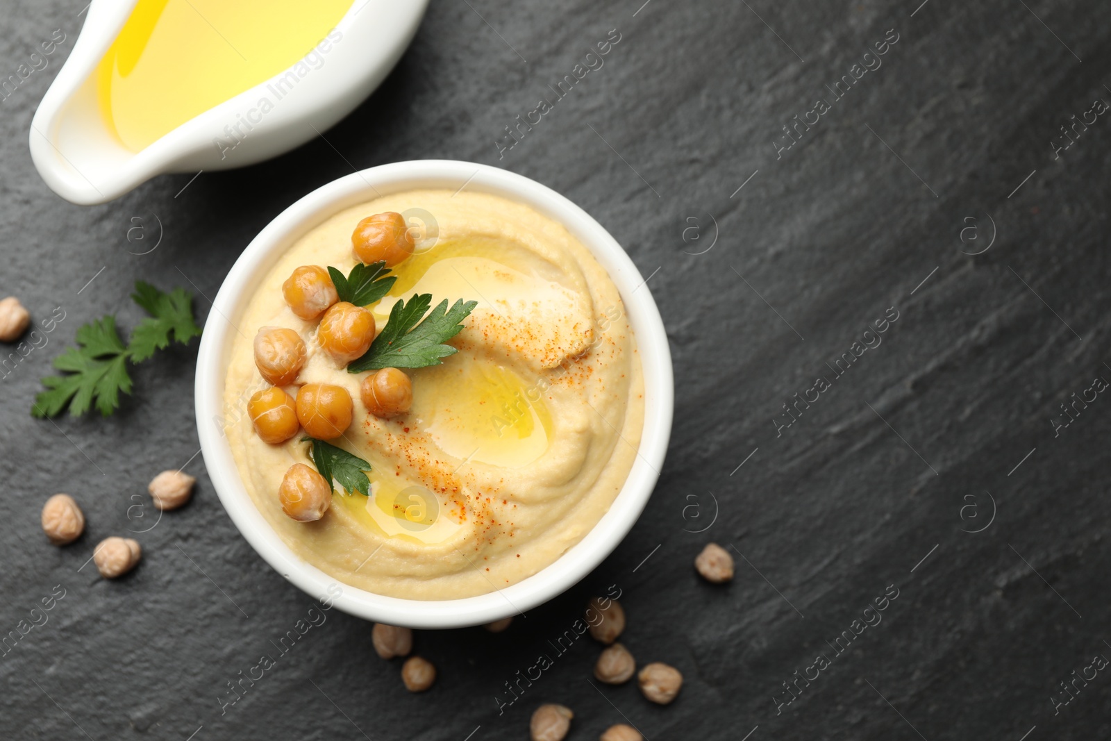 Photo of Delicious hummus with olive oil, chickpeas and parsley on grey textured table, flat lay. Space for text