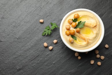 Photo of Delicious hummus with olive oil, chickpeas and parsley on grey textured table, flat lay. Space for text