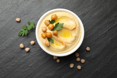 Photo of Delicious hummus with olive oil, chickpeas and parsley on grey textured table, flat lay