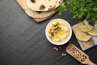 Photo of Delicious hummus with olive oil and chickpeas served on grey textured table, flat lay. Space for text