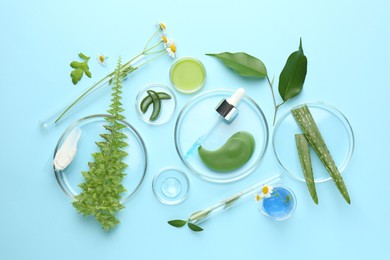 Photo of Petri dishes with different fresh leaves, chamomile flowers and cosmetic products on light blue background, flat lay