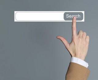 Image of Woman using search bar on virtual screen against grey background, closeup