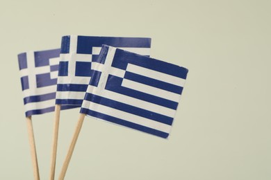 Small paper flags of Greece on light background, space for text