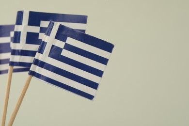 Photo of Small paper flags of Greece on light background, space for text