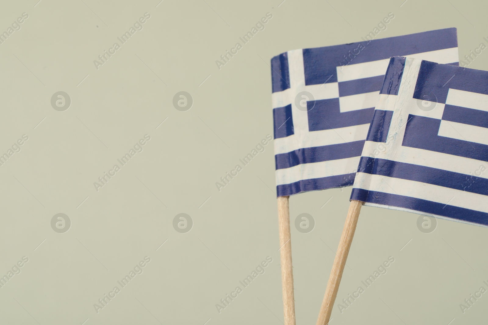 Photo of Small paper flags of Greece on light background, space for text