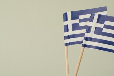 Photo of Small paper flags of Greece on light background, space for text