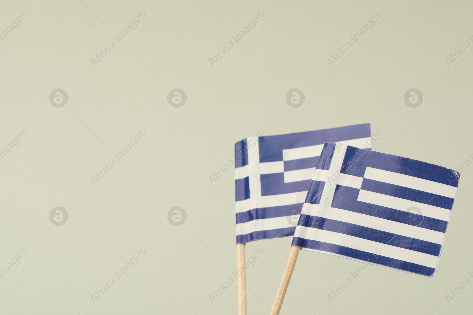 Photo of Small paper flags of Greece on light background, space for text